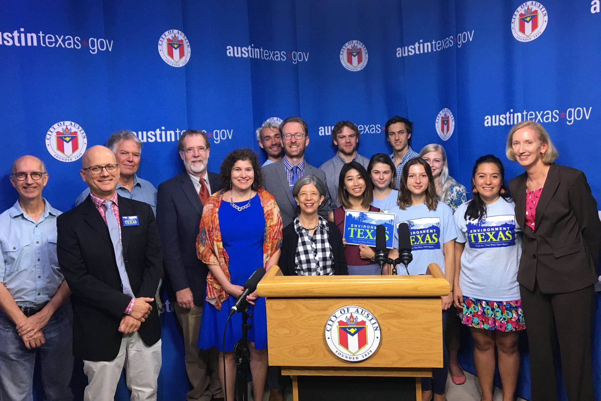 Group posing beside Austin TX podium and austintexas.gov banner