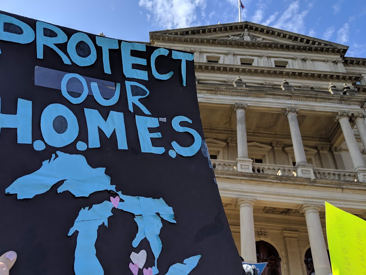 Sign outside Michigan capitol: Protect our H.O.M.E.S., with image of the Great Lakes. Credit Jen Schlicht