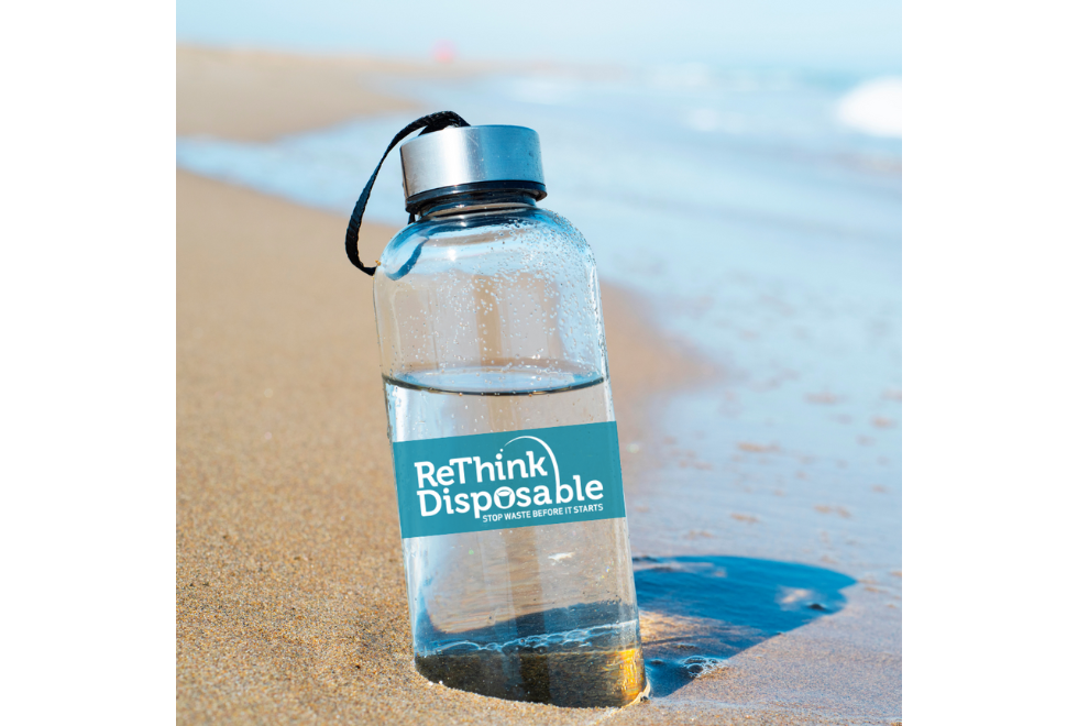 Image of a beach with a reusable water bottle and ReThink Disposable logo on it
