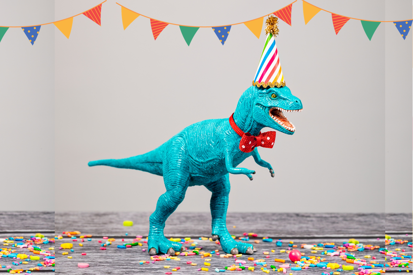 Image of a plastic dinosaur with a party hat on.