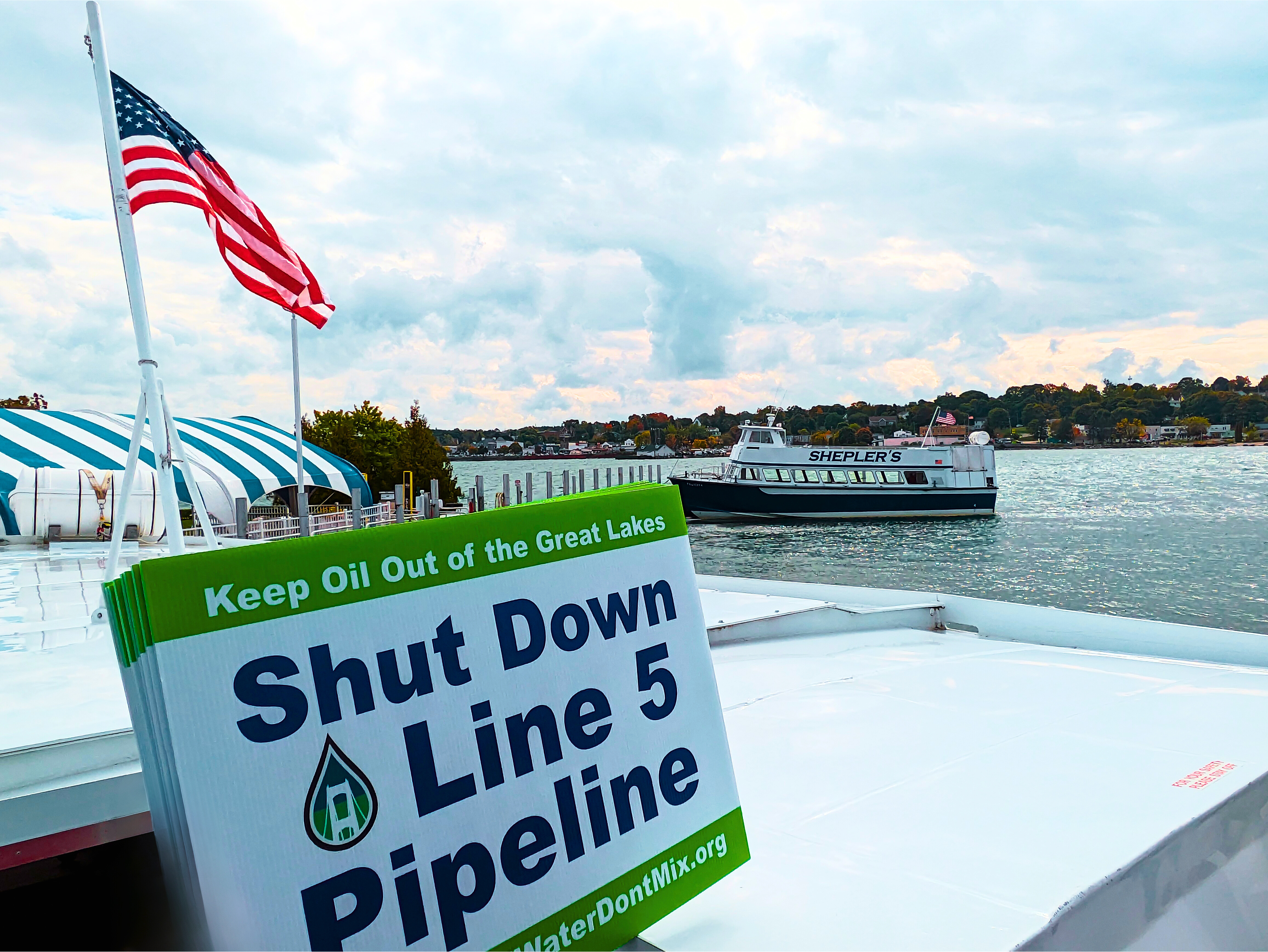 Shut Down Line 5 Pipeline sign held on a boat in the Mackinac Straits between Lake Michigan and Lake Huron
