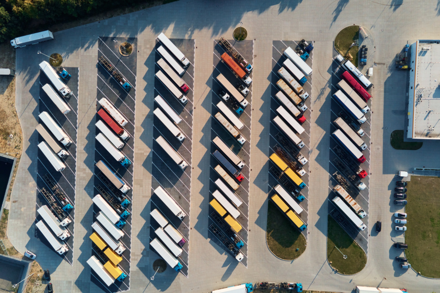 Image of a bunch of trucks in a parking lot by a warehouse - Canva