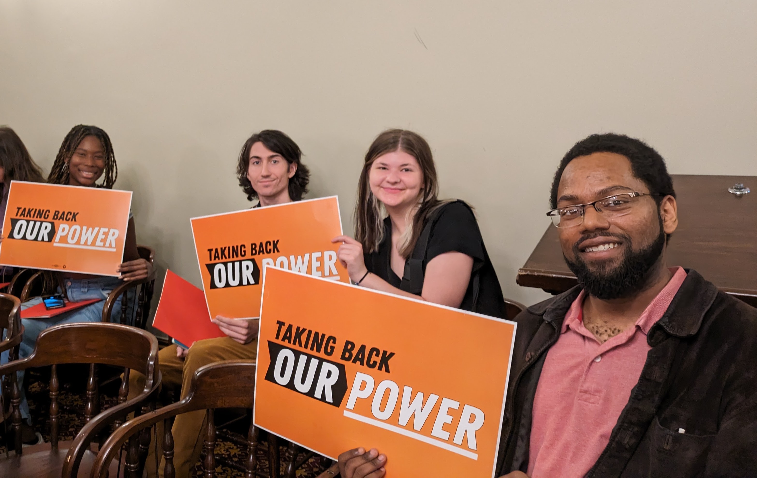 MI staff posing with "Taking Back Our Power" signs