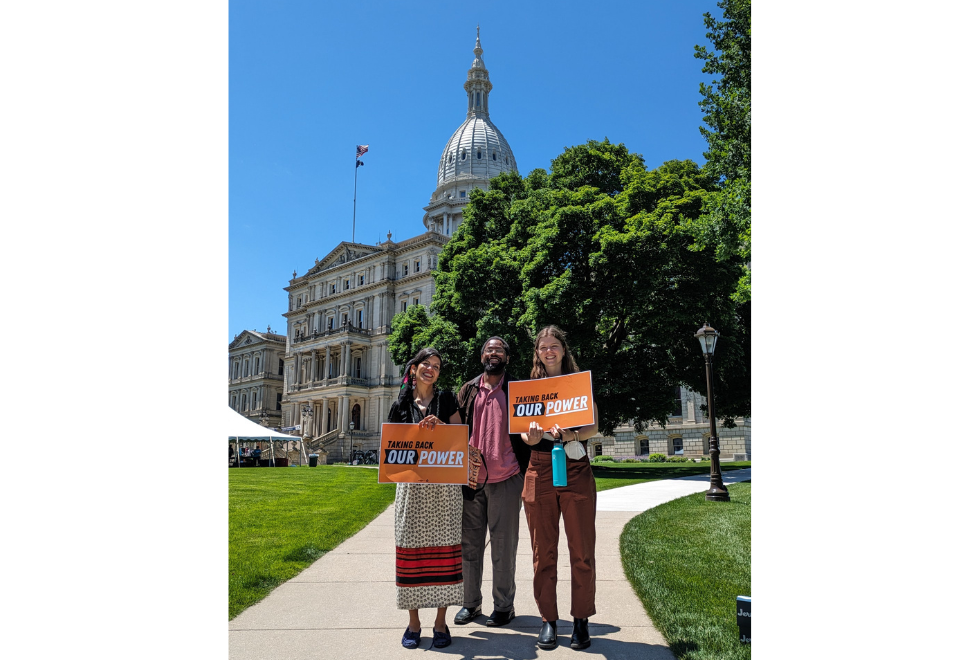 Clean Water Action staff posing by Michigan Capitol with "Taking Back Our Power" signs