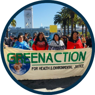 Group of Latinx activists at a rally holding a large banner reading "GREENACTION: For health & environmental justice"