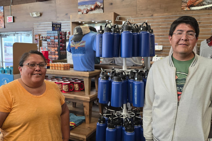 Two employees pose near a rack of reusable water bottles for sale in a gift shop