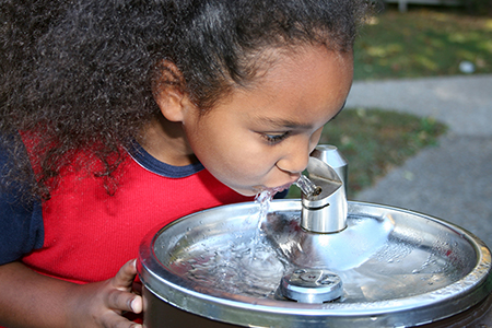 Young girl drinking from a water fountain