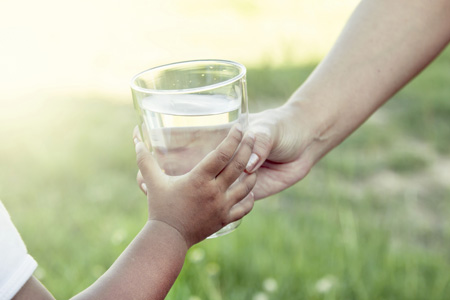 递给一个孩子一杯水。图片来源:iStock