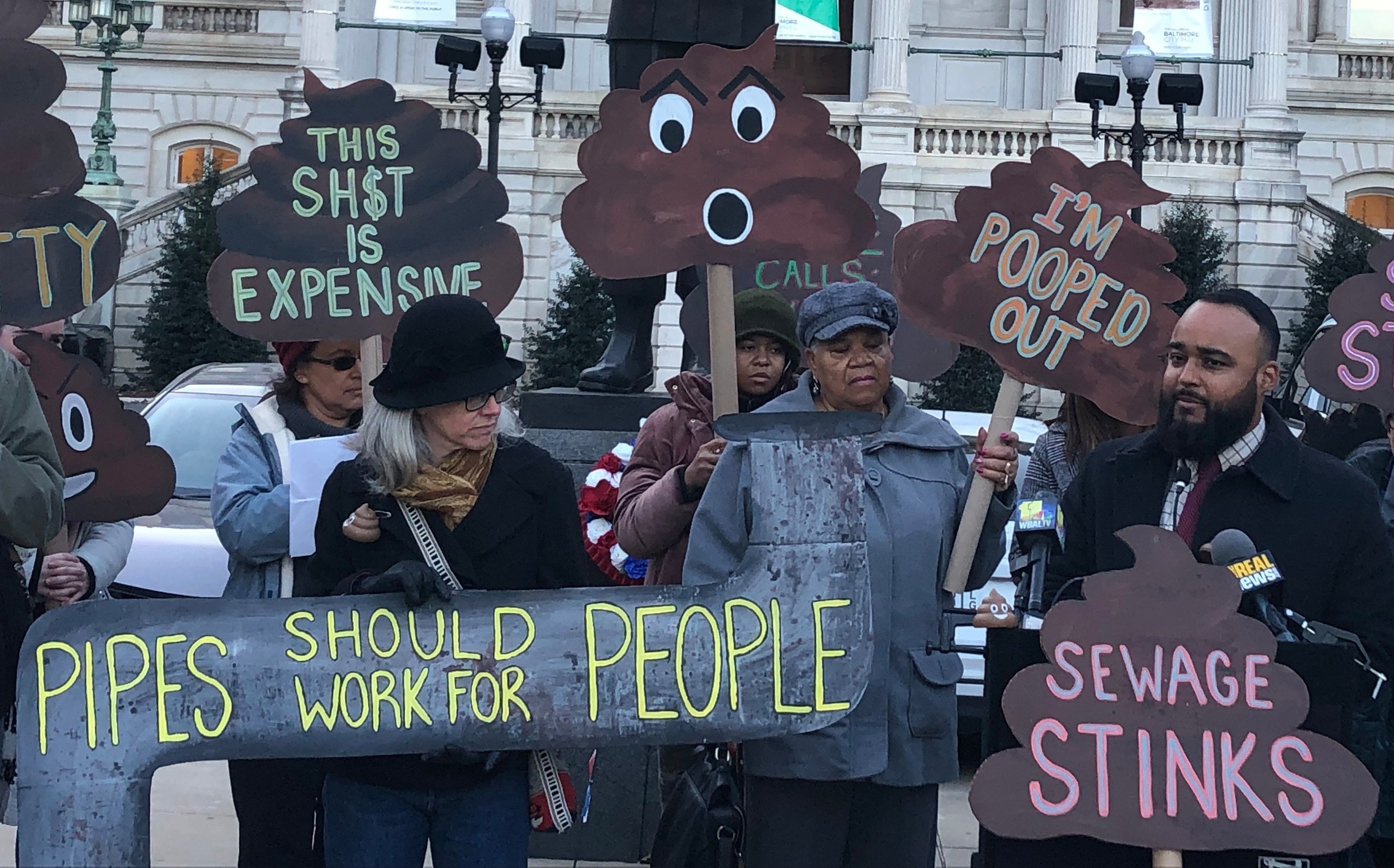People rallying in front of Baltimore City Hall holding signs like "Pipes should work for People."