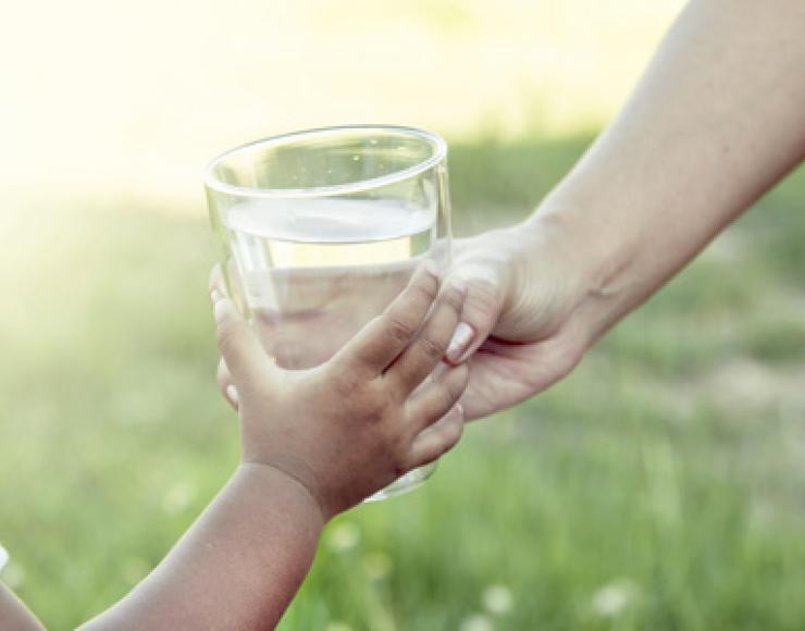 Handing a glass of water to a child. Photo credit: iStock