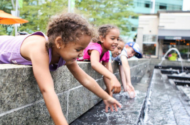 Children playing in outdoor water fountain 