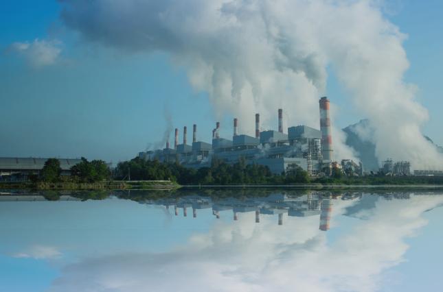 Image of a coal fired power plant by a body of water. Canva image.