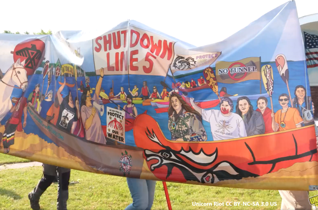 Shut Down Line 5 banner from Wisconsin Protest including "No Tunnel" "Protect Our Water", and Indigenous activists