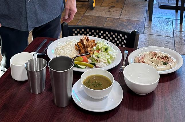 Manager of Falafal Etc posing next to a new place setting of all-reusable foodware