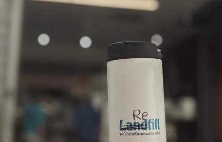 Reusable coffee mug with scribble over the word "Landfill" to read "Refill". Rethinkdisposable.org