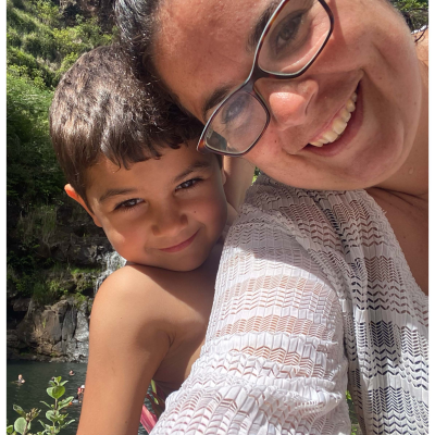 A picture of Gabi Sanchez and a young child. Gabi has her head at the top of the frame sideways, wearing glasses and a white shirt.