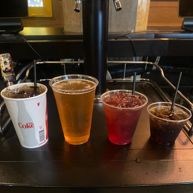 Lineup of disposable cups of various sizes, plastic and wax paper with straws.
