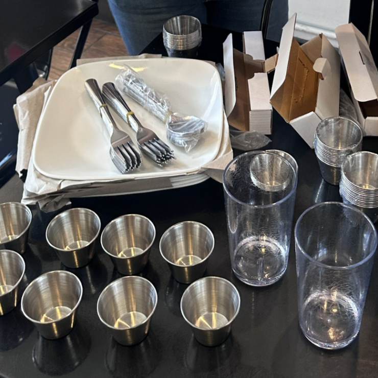 Stainless steel utensils and sauce cups next to reusable cups