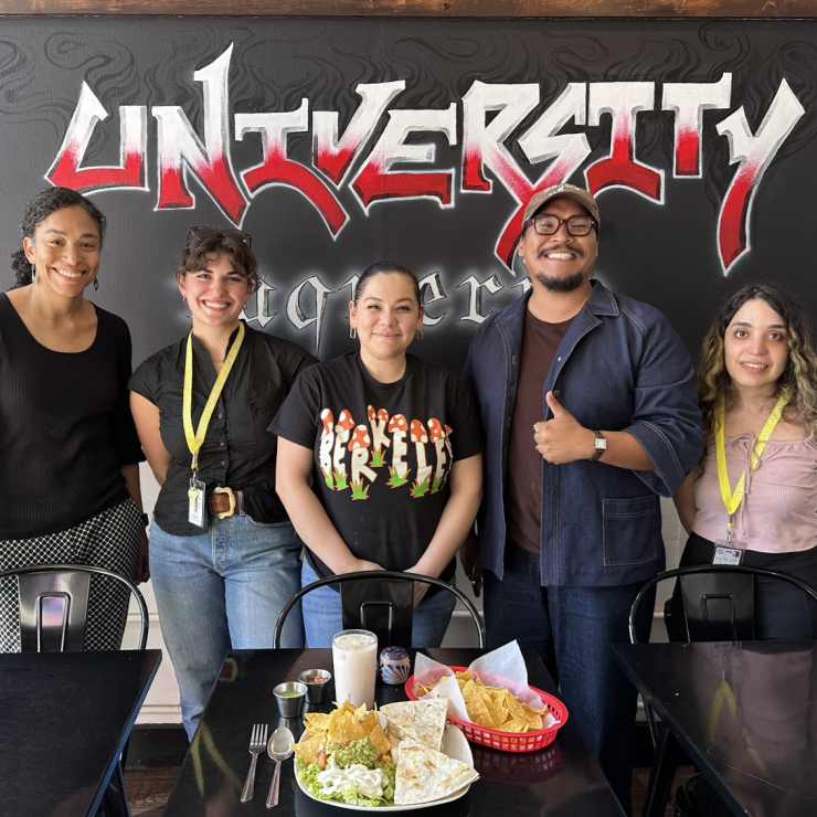 Five staff members from University Taqueria showing off a dine-in table setting with reusable cups and utensils