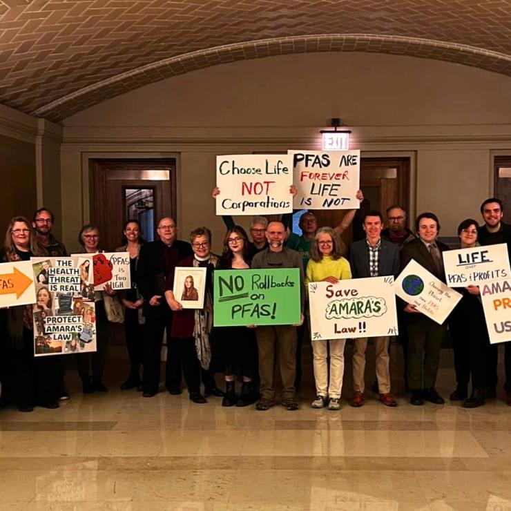 People holding signs like "PFAS Are Forever, Life Is Not" at a rally in the MN State Capitol