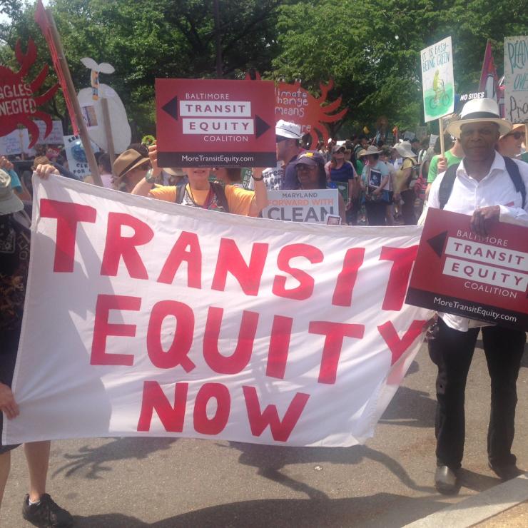Supporters of the Baltimore Transit Equity Coalition hold a sign that reads "Transit Equity Now"