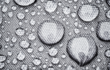Raindrops beading on waterproof fabric possibly treated with PFAS