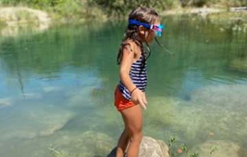 Young Texas girl in swim suit and snorkel on water's edge