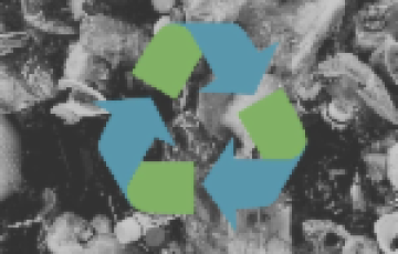 Blue and green chasing-arrows recycling symbol against a background of black and white trash