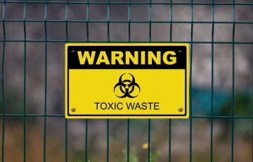 Photo: Sign that says Warning Toxic Waste on a fence. From Canva.