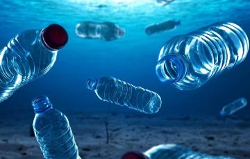 Image of plastic water bottles floating in blue water. Source: Canva