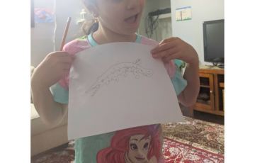 Child holding a drawing of a gar fish