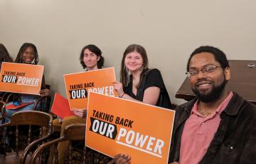 MI staff posing with "Taking Back Our Power" signs