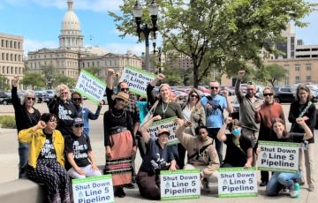 Outside the Michigan capitol building with Shut Down Line 5 Pipeline signs
