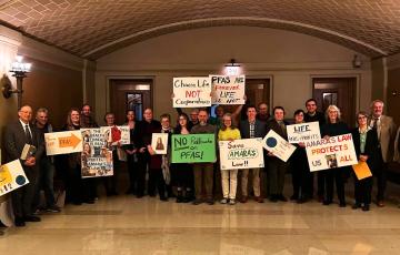 People holding signs like "PFAS Are Forever, Life Is Not" at a rally in the MN State Capitol