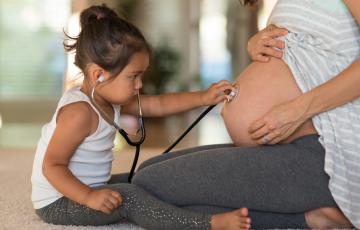 toddler with stethoscope listening to pregnant belly. photo: istock