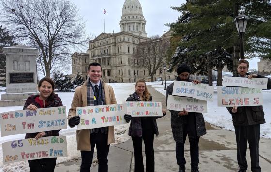 Michigan canvass staff holding shut down line 5 / no tunnel signs outside Lansing capitol building in 2018. Credit: Jennifer Schlicht