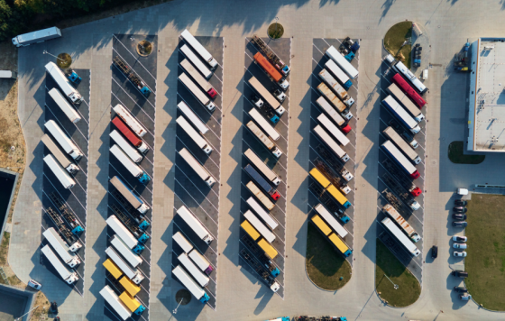 Image of a bunch of trucks in a parking lot by a warehouse - Canva