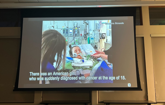 Still from documentary film of Amara Strande in hospital bed with caption "There was an American girl who was suddenly diagnosed with cancer at the age of 15"