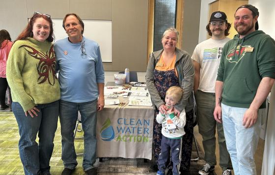 Clean Water staff and guests pose by a table with Earth Day coloring pages