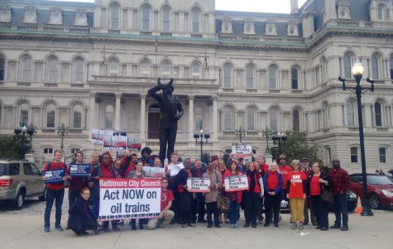 Over 30 Baltimore residents outside of City Hall wearing red in support of the Oil Trains Ordinance and the Fracking Ban